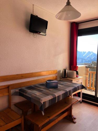 Cette chambre dispose d'une table et d'une télévision murale. dans l'établissement Studio 4 pers Soleil d'Huez - maeva Home - Studio 4 Personnes Confort MAE-5688, à L'Alpe-d'Huez