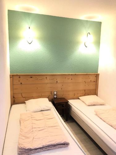 - 2 lits dans une chambre avec 2 lumières sur le mur dans l'établissement Résidence Les Bergers - maeva Home - Studio 4 personnes Budget MAE-9504, à Huez
