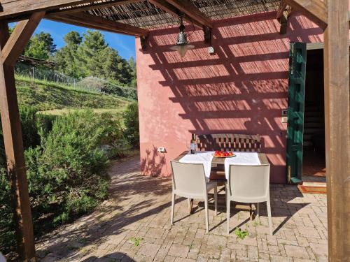 a table and chairs sitting under a wooden pergola at Agriturismo Piccolo Paradiso in Riparbella