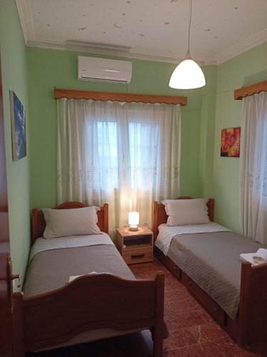 two beds in a room with green walls and a window at Kalotina's House in Kalymnos