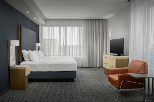 a hotel room with a bed and a television at Courtyard by Marriott Muncie at Horizon Convention Center in Muncie