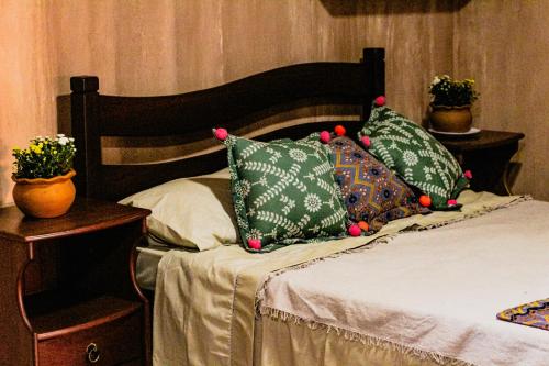 a bed with green pillows on it with two plants at Bossa Kite House in Cumbuco