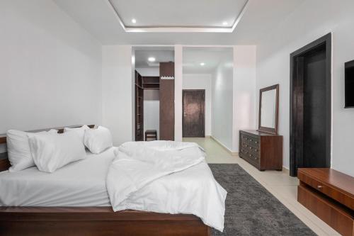 Un dormitorio con una cama con sábanas blancas y un televisor. en T0T3 Homes, en Lagos