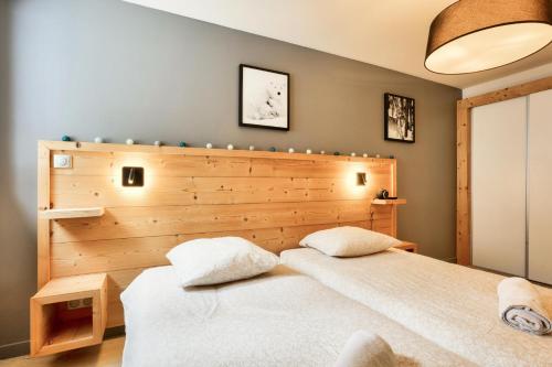 two beds in a bedroom with a wooden headboard at Résidence les Chardons - maeva Home - Appartement chaleureux 4 pièces 8 personnes - Prestige - super Home MAE-3341 in Arc 1800