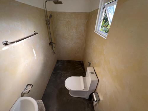 a bathroom with a toilet and a sink and a window at Marigold Negombo in Negombo