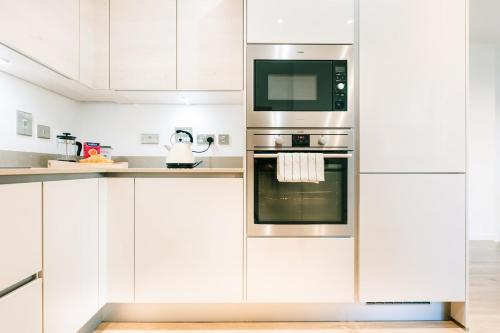 a kitchen with white cabinets and stainless steel appliances at Peaceful Apartment in East End in London