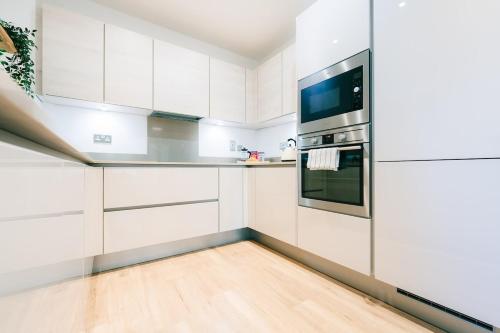 a kitchen with white cabinets and a stainless steel refrigerator at Peaceful Apartment in East End in London