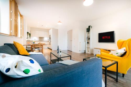 a living room with a blue couch and yellow chairs at Peaceful Apartment in East End in London