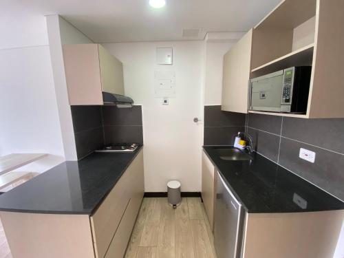 a small kitchen with black countertops and white cabinets at Suite de Lujo en Llano Grande - Piscina, jacuzzi, Turco, Gimnasio in Rionegro