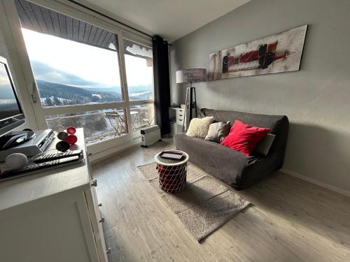 a living room with a couch and a large window at Au pied des pistes Côte 2000 - Le Balcon de Villard de Lans in Villard-de-Lans