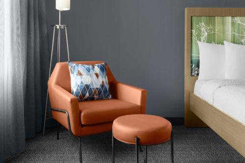 an orange chair in a room next to a bed at Courtyard by Marriott Orlando South/Grande Lakes Area in Orlando