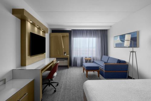 a hotel room with a bed and a couch and a television at Courtyard by Marriott Orlando South/Grande Lakes Area in Orlando