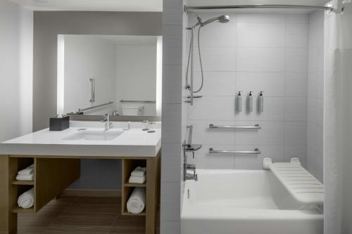 a bathroom with a sink and a tub and a shower at Courtyard by Marriott Orlando South/Grande Lakes Area in Orlando