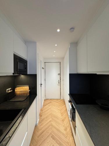 une cuisine avec des armoires blanches et des comptoirs noirs dans l'établissement 2 bedroom apartment renovated in the heart of Paris, à Paris