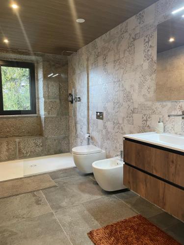 a bathroom with two sinks and a toilet and a tub at Casa Videira in Gouveia
