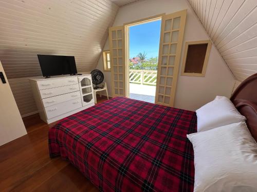 a bedroom with a bed and a tv in a room at Chalé Condomínio Vila Suiça - Balneário Rincão in Vila Nova