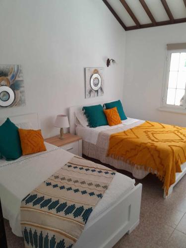 a bedroom with two beds with orange and blue pillows at Quinta da Baldaia in Rabo de Peixe