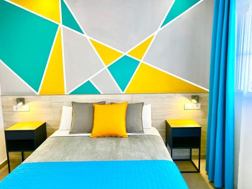a bedroom with a bed with a colorful wall at DORI ROOMS - Hostal in Tarifa