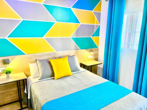 a bedroom with a bed with a colorful wall at DORI ROOMS - Hostal in Tarifa