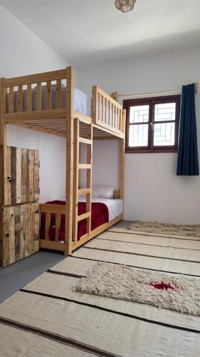 a bedroom with two bunk beds and a rug at Chambre familiale à fisherman house in Wassane