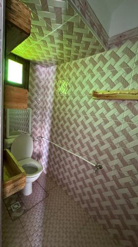 a bathroom with a toilet and a wall at Chambre familiale à fisherman house in Wassane