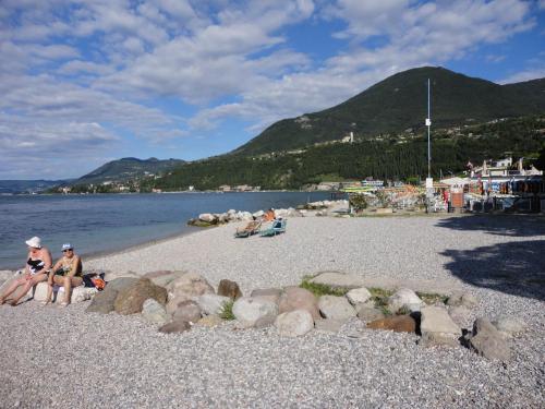 two women sitting on a rocky beach near the water at Ferienwohnung Maderno in Affoltern