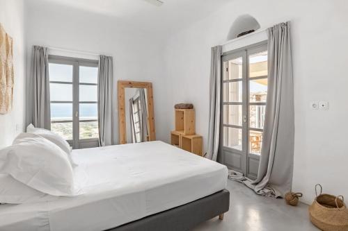 a white bedroom with a large bed and windows at Horizon House with private pool and breathtaking views in Andiparos