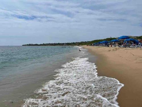 a beach with a person walking in the water at Perfect location! Minutes to beaches! Beach pass! in Barnstable