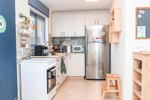 a kitchen with white cabinets and a stainless steel refrigerator at אתנחתא- צימר משפחתי - Etnachta- A family hosting unit in Yeroẖam