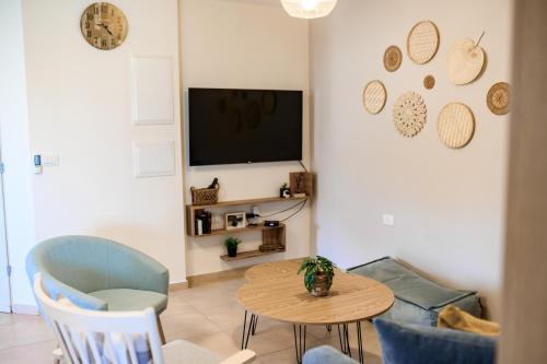 a living room with a table and chairs and a tv at אתנחתא- צימר משפחתי - Etnachta- A family hosting unit in Yeroẖam