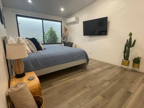 a bedroom with a bed and a flat screen tv at Casa Tres Luces - Samara Home in Nicoya
