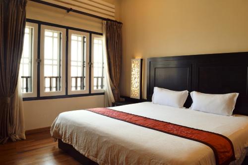 a bedroom with a large bed and two windows at Jonker Boutique Hotel in Melaka