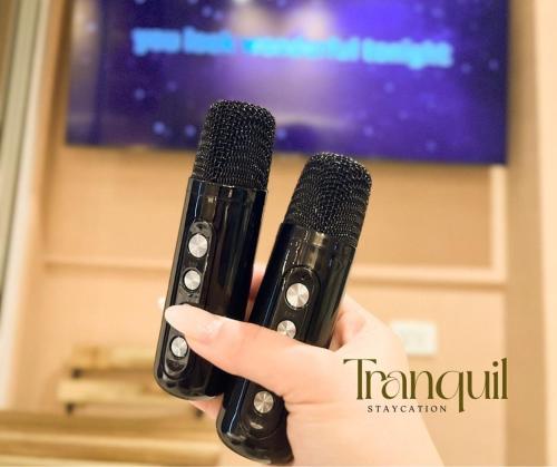 Una persona que sostiene dos micrófonos frente a un televisor. en Tranquil Staycation at Azure, en Manila