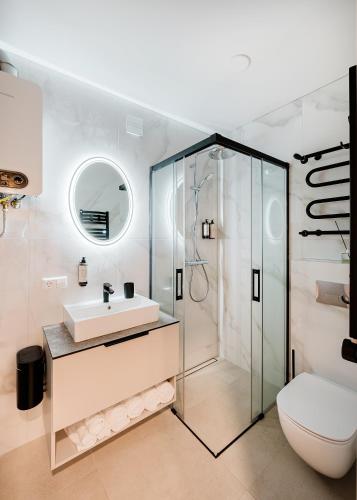 a bathroom with a glass shower and a sink at King Mindaugas center apartment in Kaunas
