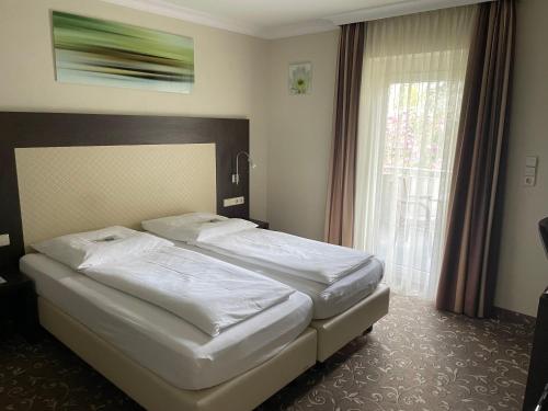 a bedroom with two beds and a large window at Hotel Ochsen Stuttgart in Stuttgart