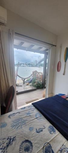 a bedroom with a bed and a view of the ocean at Suites Villa Forte Santana in Florianópolis