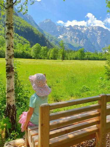 a little girl sitting on a bench looking at the mountains at Weiss Sport & Relax Apartment in Rečica ob Savinji