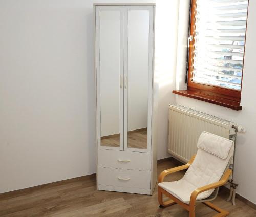 a white cabinet and a chair in a room at Weiss Sport & Relax Apartment in Rečica ob Savinji