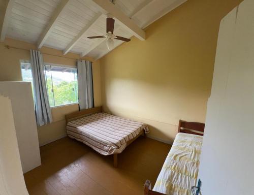 a room with two beds and a ceiling fan at Rosa blue in Imbituba