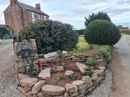 a garden in front of a house with a stone wall at Upper Eyton Farmhouse B&B in Shrewsbury