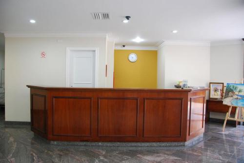 un escritorio de madera en una habitación con reloj en la pared en AGUAS DE SÃO PEDRO VIP, en Águas de São Pedro