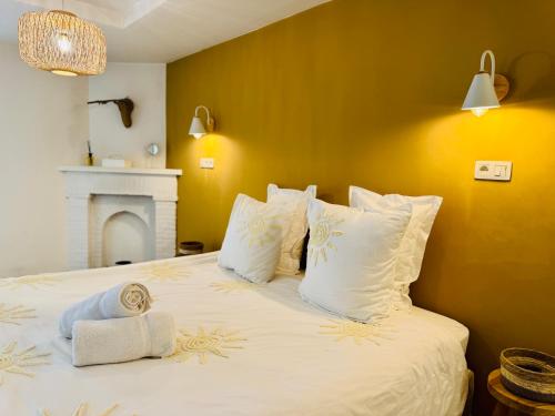 a bedroom with a bed with white pillows and a fireplace at Oboho - Le gîte bohème (Pieds dans l’eau - Lit King Size - Jardin) in Esneux