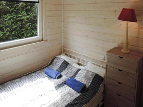 ein Schlafzimmer mit einem Bett mit blauen Kissen und einem Fenster in der Unterkunft Bungalow in Kolczewo near Baltic Sea & Lakes in Kołczewo