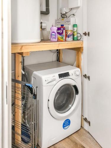 a laundry room with a washer and dryer on a shelf at 1-BR Flat next to Heathrow Airport London, 3-Beds, Free Parking in Harmondsworth