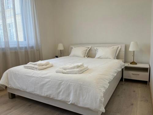 a white bed with white towels on top of it at Elegant Escape Apartment I - City Centre & Free Parking in Bratislava
