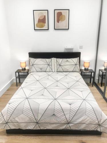 a bed with a black and white comforter in a bedroom at 1-BR Flat next to Heathrow Airport London, 3-Beds, Free Parking in Harmondsworth