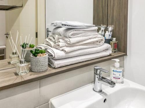a stack of towels on a shelf above a sink at 1-BR Flat next to Heathrow Airport London, 3-Beds, Free Parking in Harmondsworth
