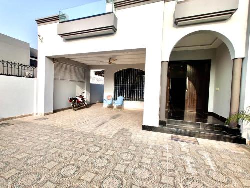 a white building with a patio with chairs and a motorcycle at Luxury Villa - 1 Kanal Furnished 5 bedrooms , DHA Phase 6 in Lahore