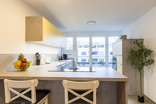 a kitchen with a island with two chairs and a counter top at living TIMELESS - Apartments zum roten Lamm- Bad Krozingen in Bad Krozingen