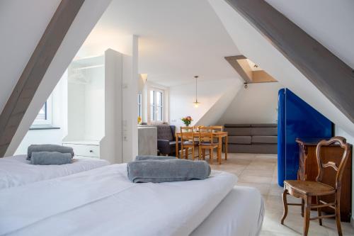 a attic bedroom with two beds and a dining room at living TIMELESS - Apartments zum roten Lamm- Bad Krozingen in Bad Krozingen